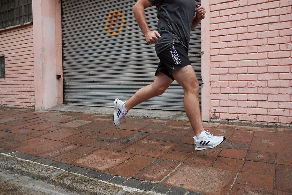 A running beginner is wearing adidas gear and running in the city