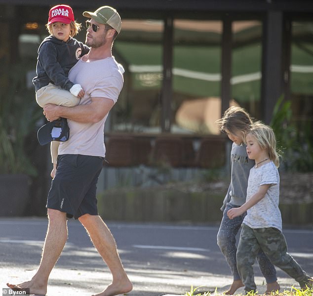 Super dad! Australian actor Chris Hemsworth was spotted carrying his injured twin son during barefoot stroll in Byron Bay with his three children on Thursday