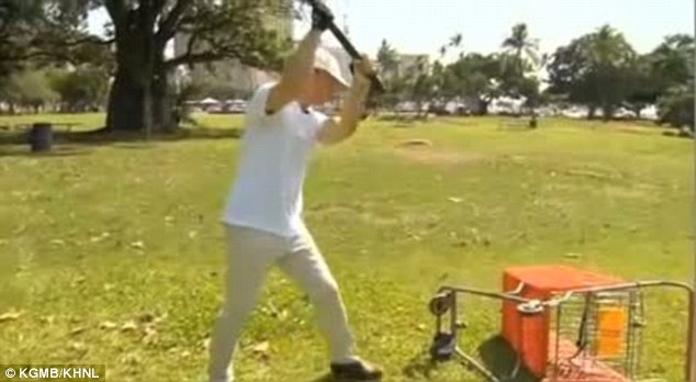 Crackdown: Hawaii state representative Tom Brower takes a sledgehammer to a shopping trolley in his war against homelessness